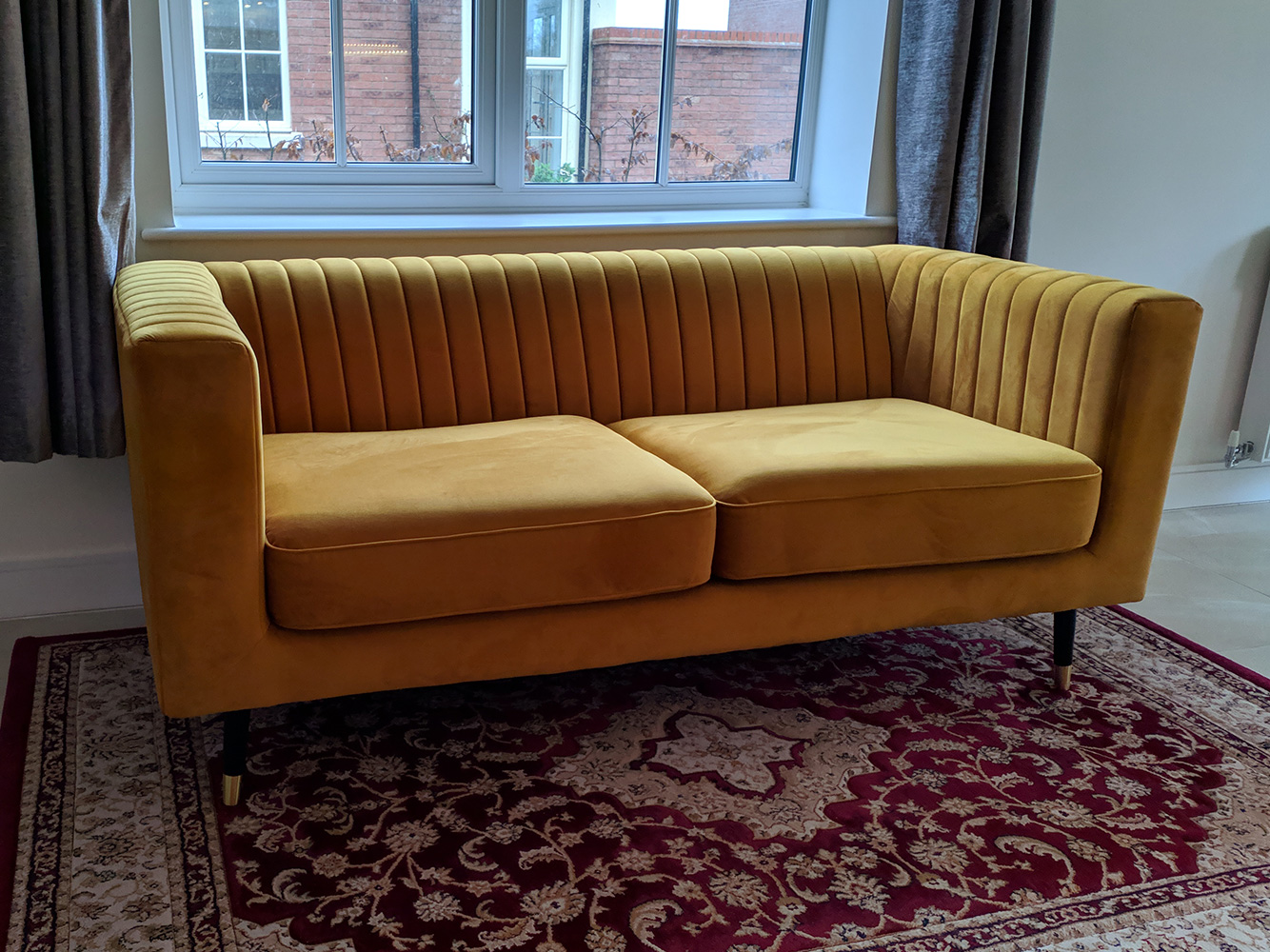Slender two-seater sofa in mustard color